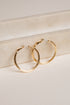 Gold hoop earrings on a light beige surface