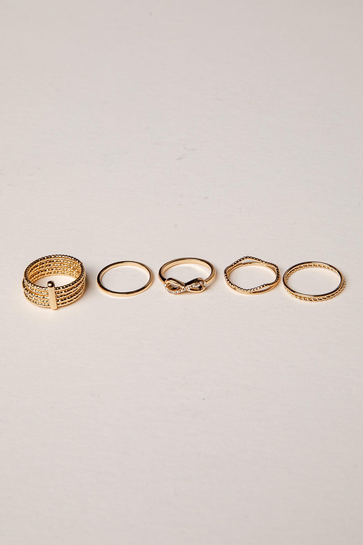 Set of five gold rings on a light gray background
