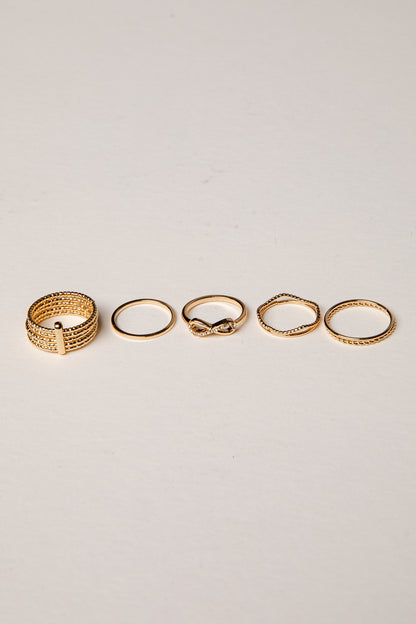 Set of five gold rings on a light gray background