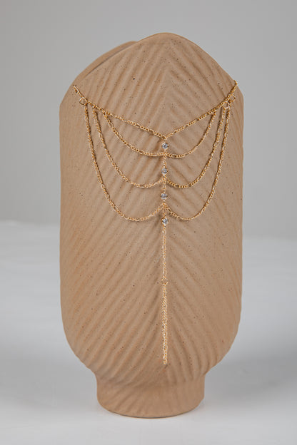Gold chain headpiece on a brown mannequin head against a gray background