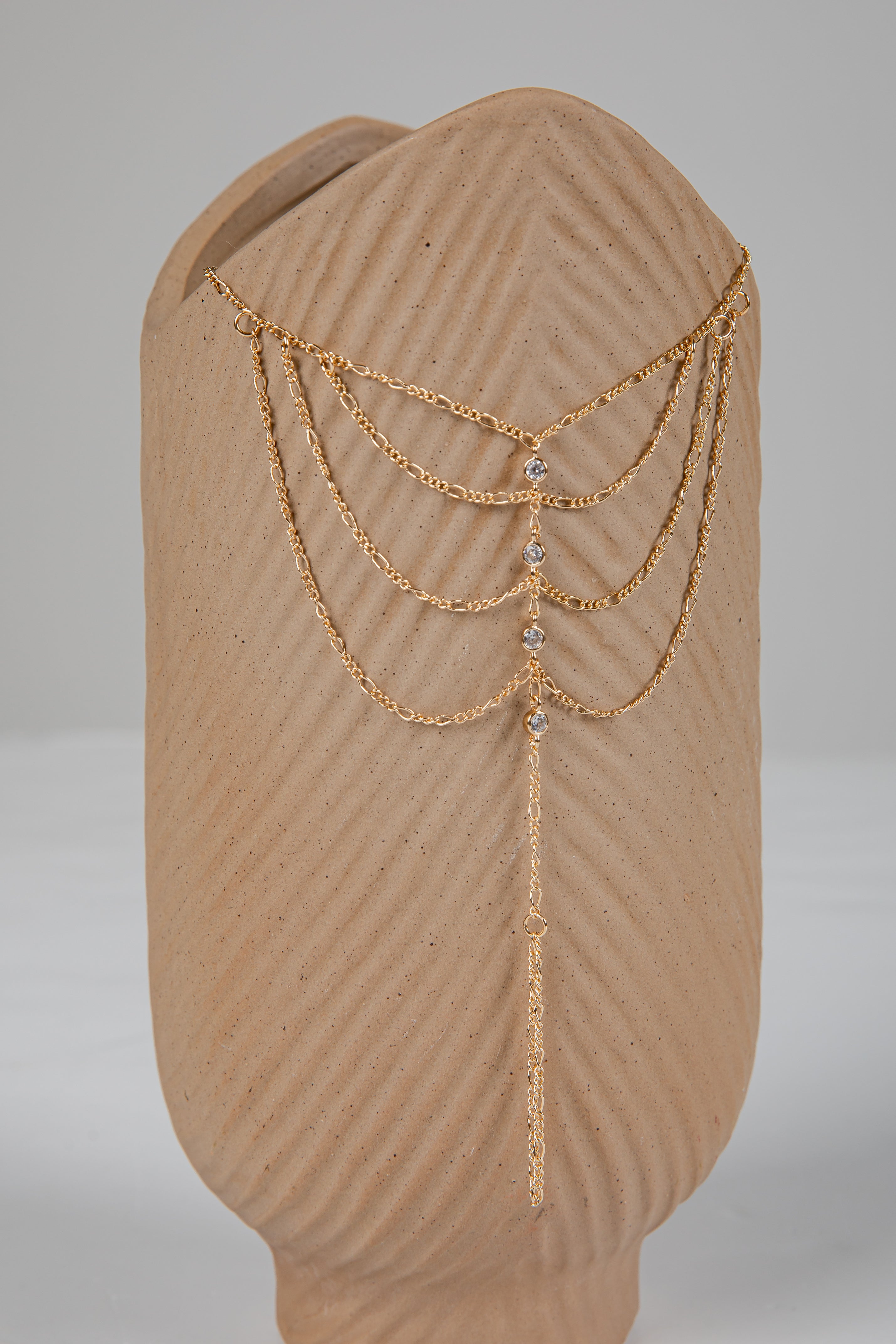 Gold chain headpiece on a mannequin head with a plain background