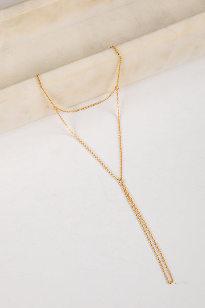 Gold necklace on a white surface with a beige background