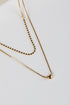 Two gold necklaces on a light gray background