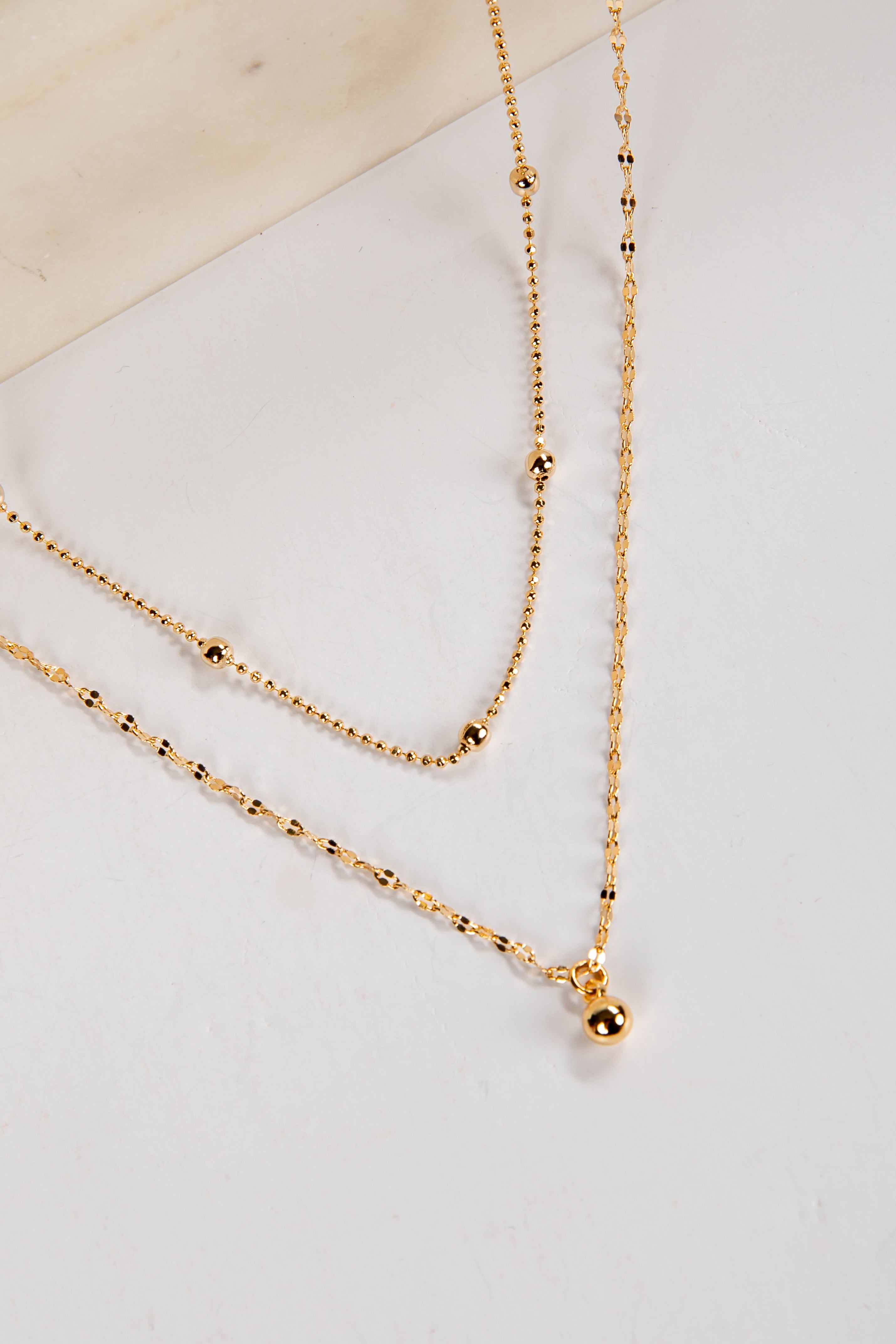 Gold necklace on a light gray surface