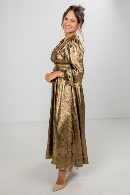 Woman wearing a gold metallic dress against a white background