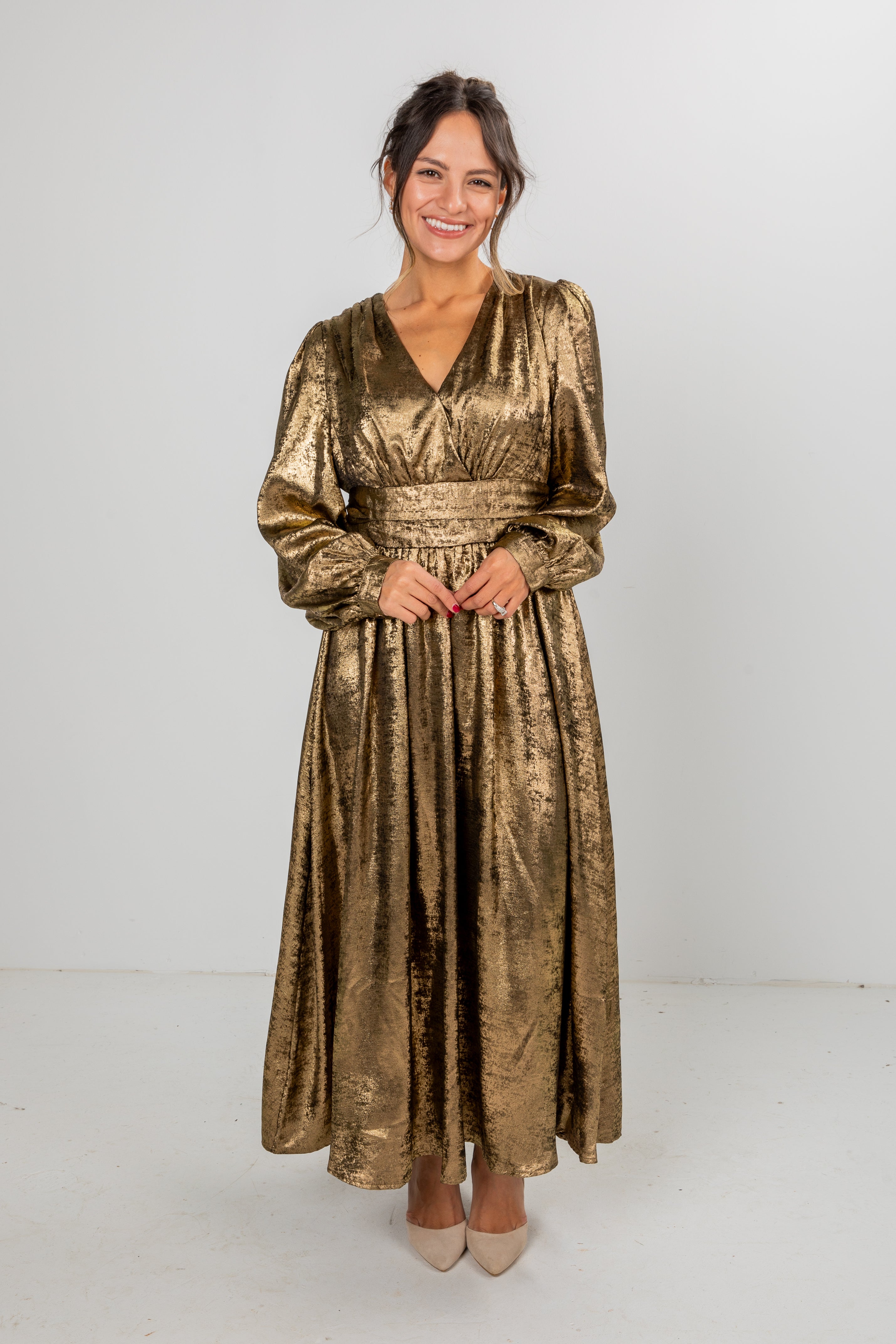 Woman wearing a gold metallic dress against a white background