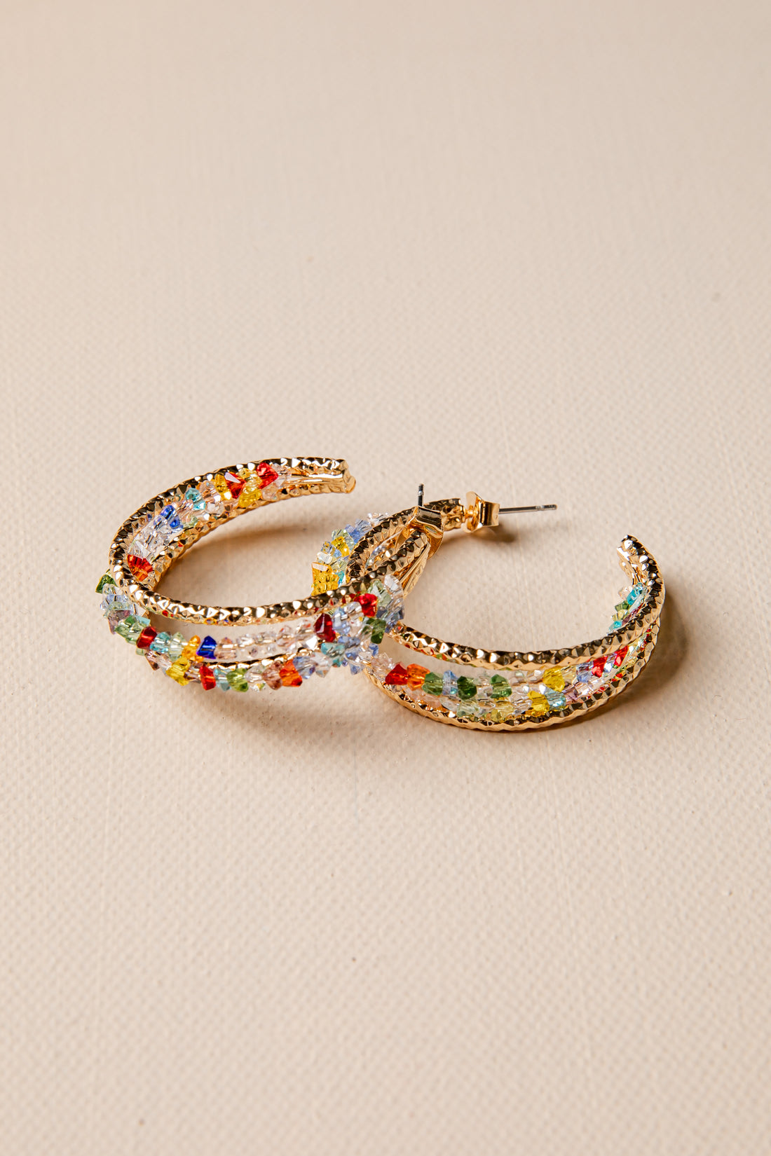 Colorful hoop earrings on a beige background