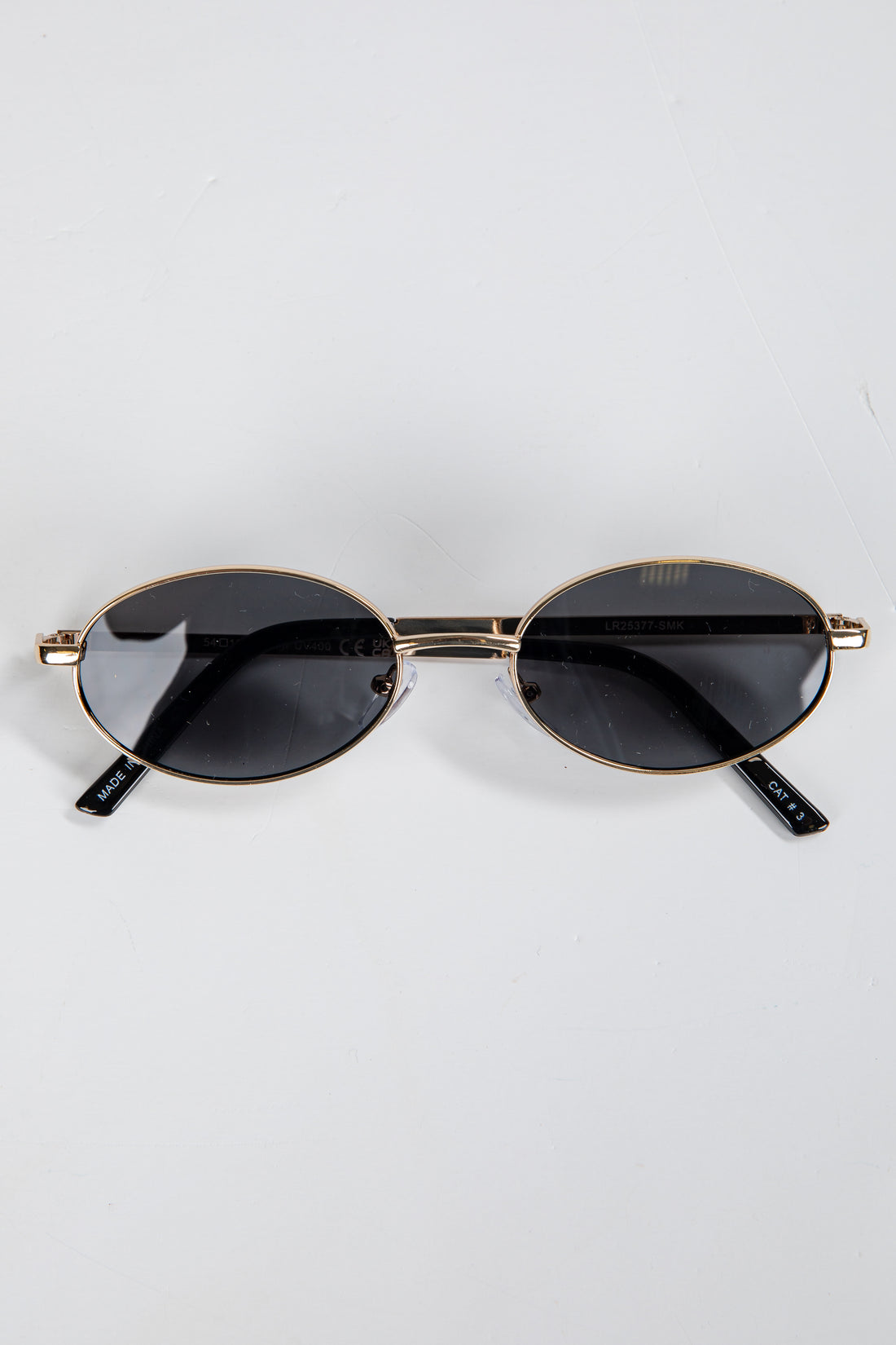 Round sunglasses with gold frame and black lenses on a white background