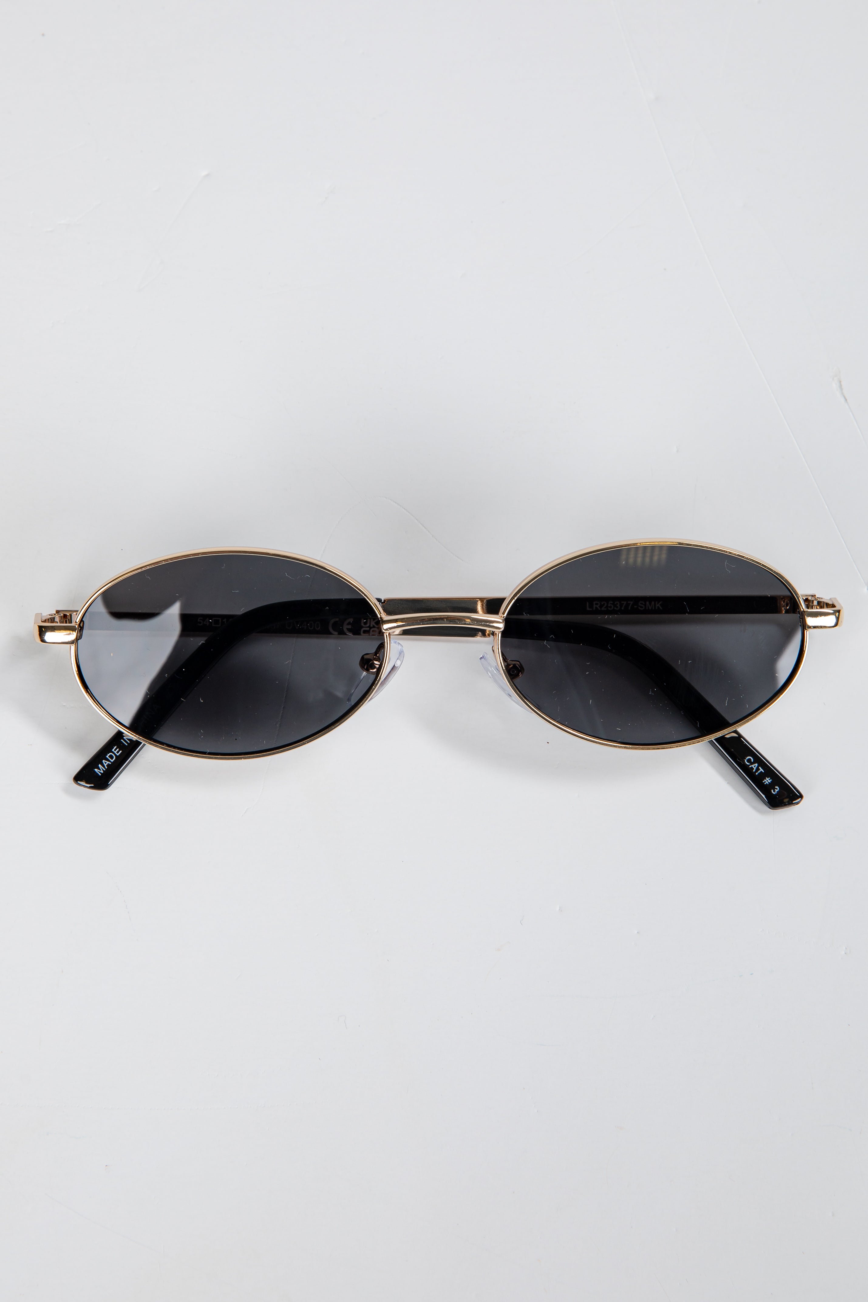 Round sunglasses with gold frame and black lenses on a white background