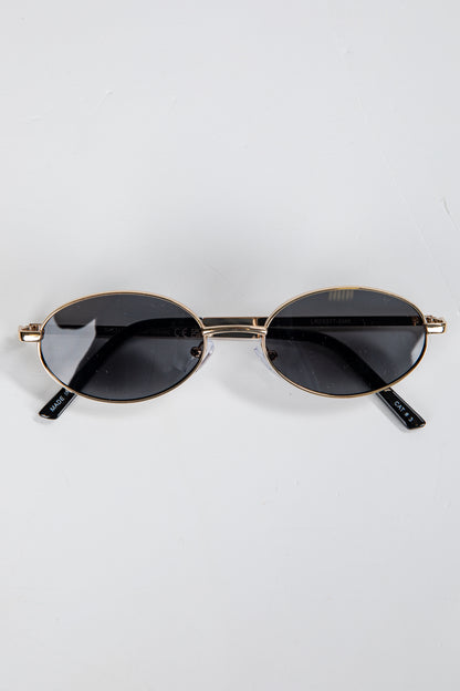 Round sunglasses with gold frame and black lenses on a white background