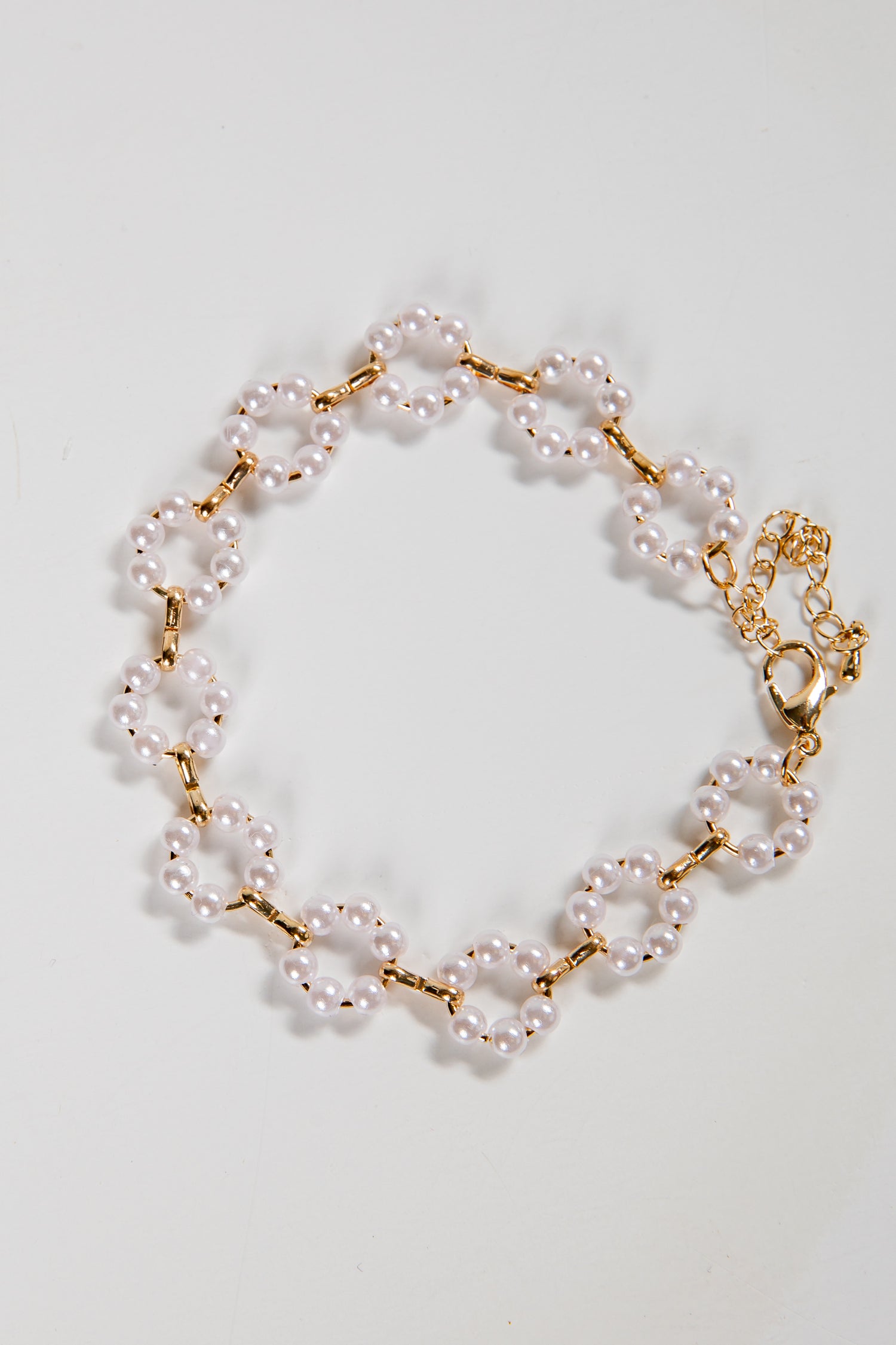 Pearl bracelet with gold chain on a light gray background