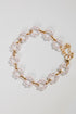 Pearl bracelet with gold chain on a light gray background