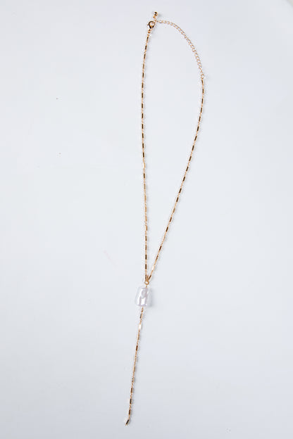 Long necklace with a clear pendant on a light gray background