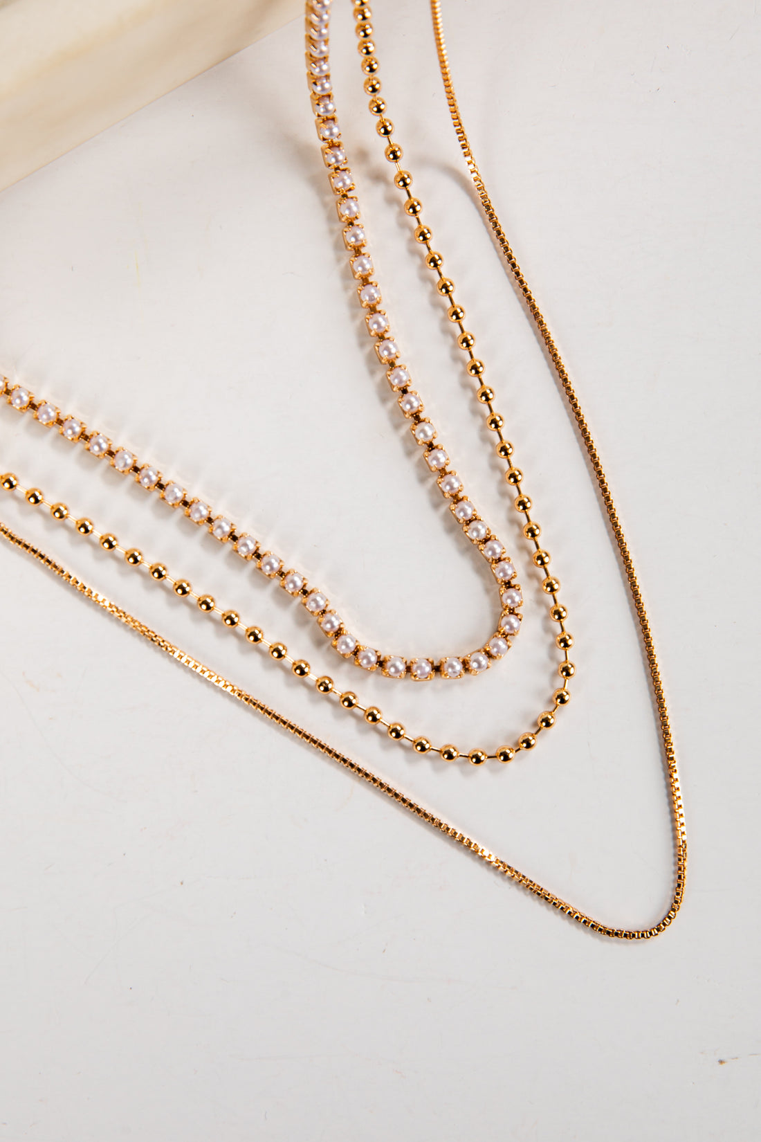 Three gold necklaces on a light background