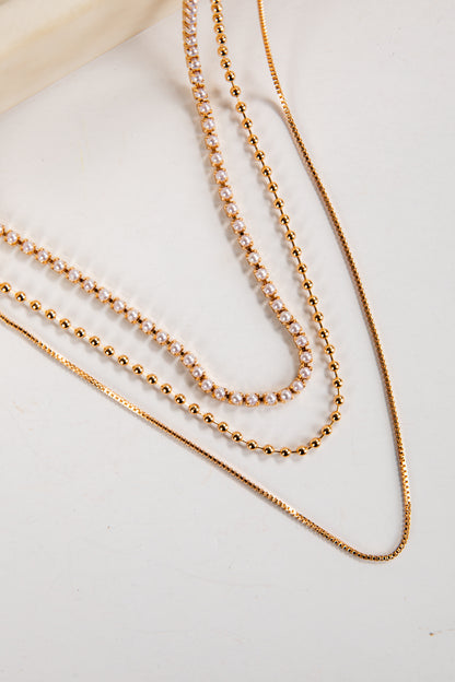 Three gold necklaces on a light background