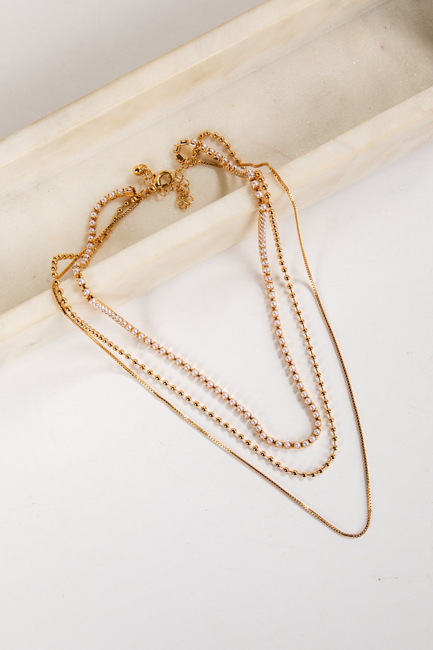 Gold necklaces on a light beige surface