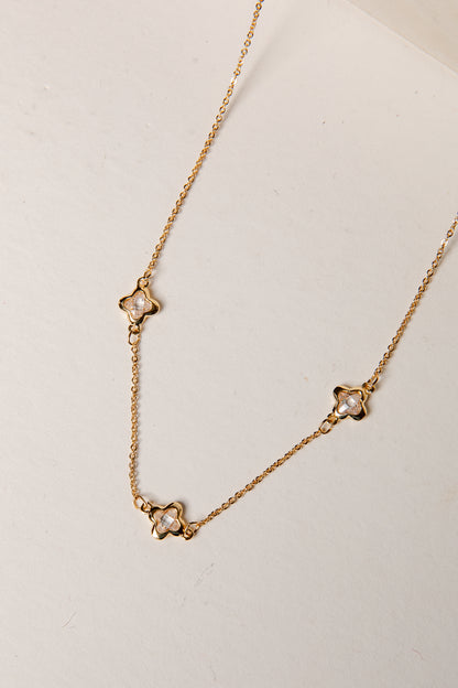 Gold necklace with star-shaped pendants on a light background