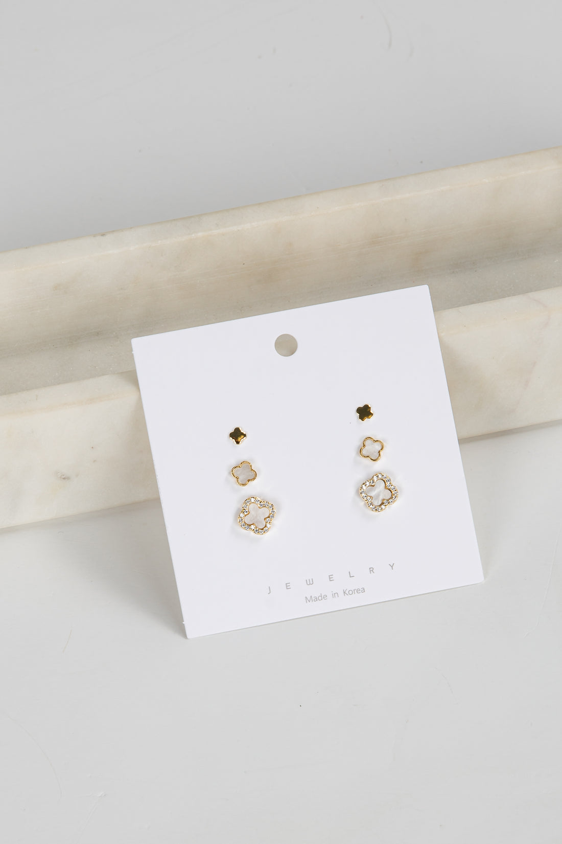 Set of gold earrings on a white card with a marble surface background