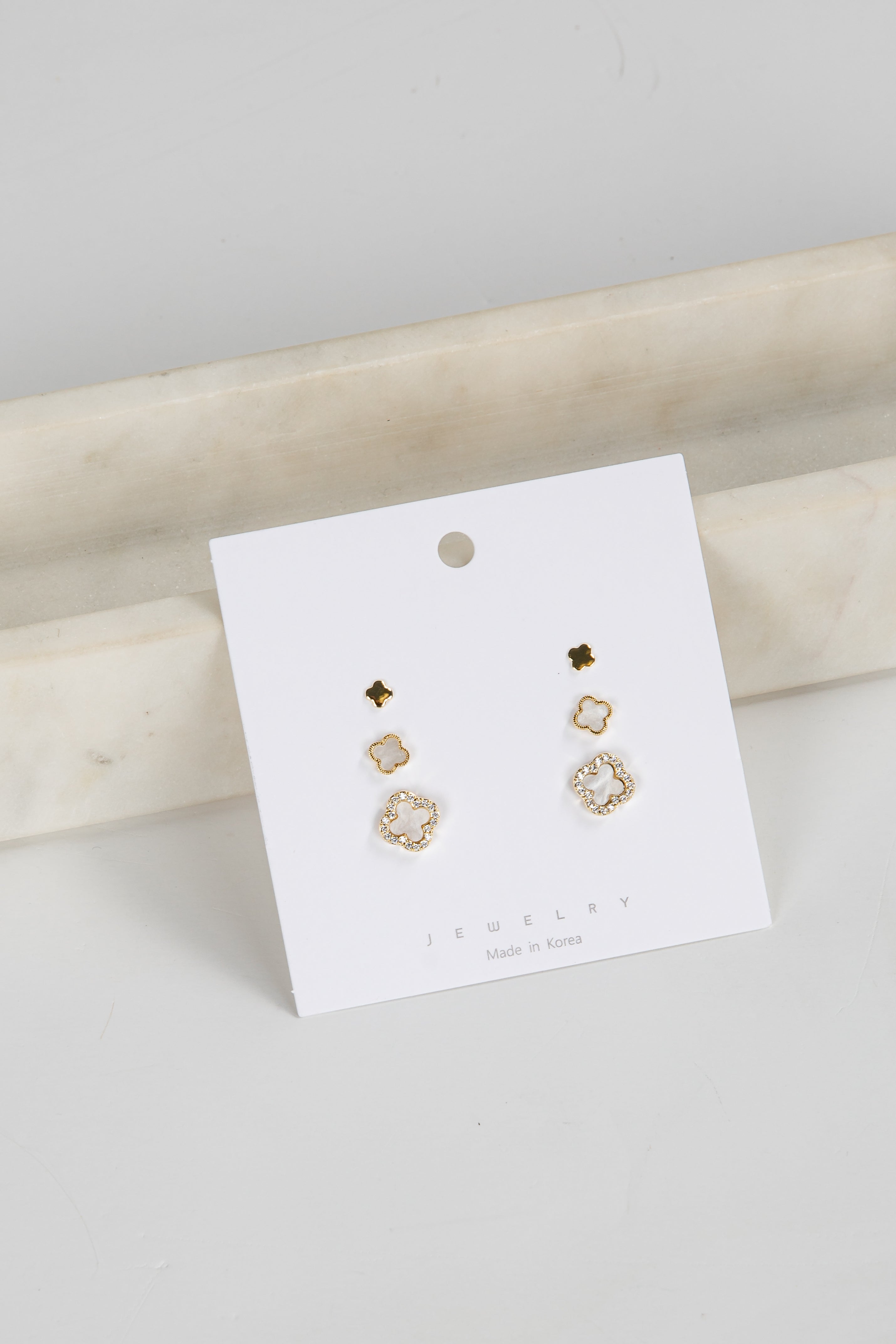 Set of gold earrings on a white card with a marble surface background