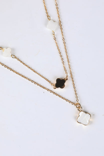Two gold necklaces with clover pendants on a white background