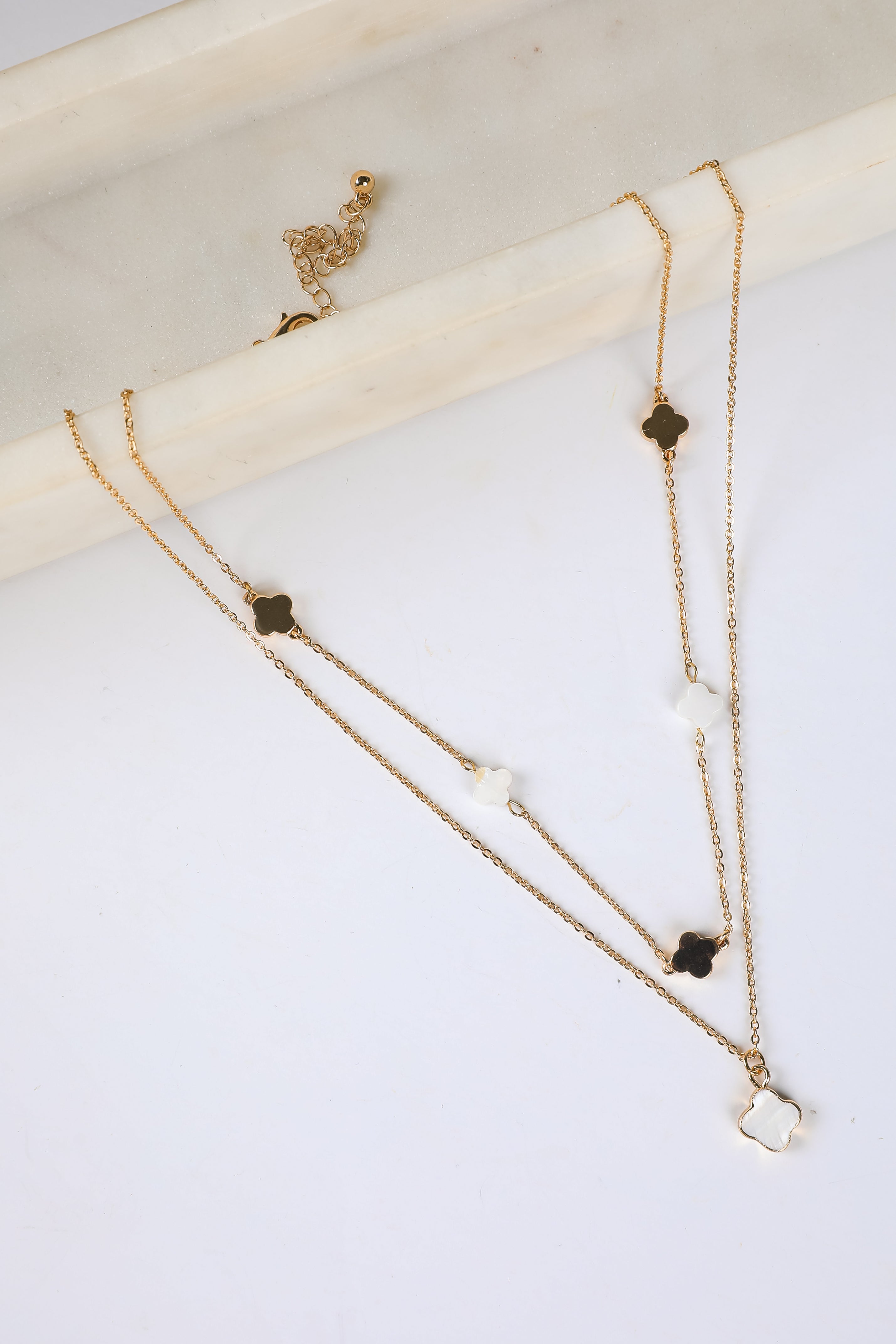 Two gold necklaces with black and white stone pendants on a white surface.