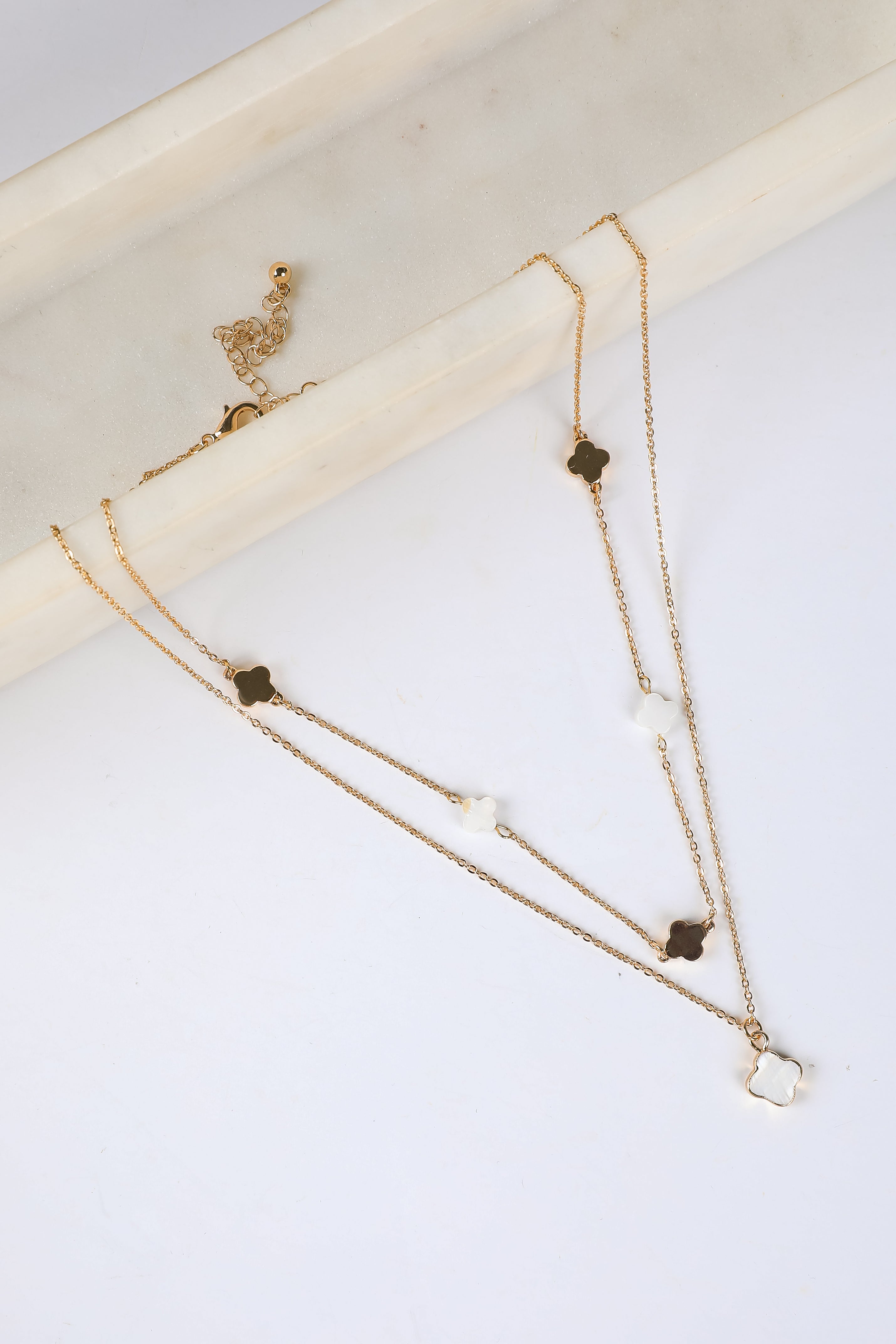 Gold necklace with small pendants on a white surface