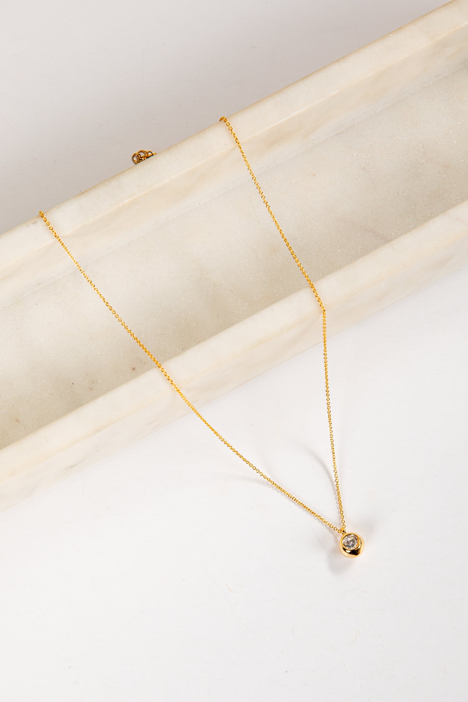 Gold necklace on a white marble surface
