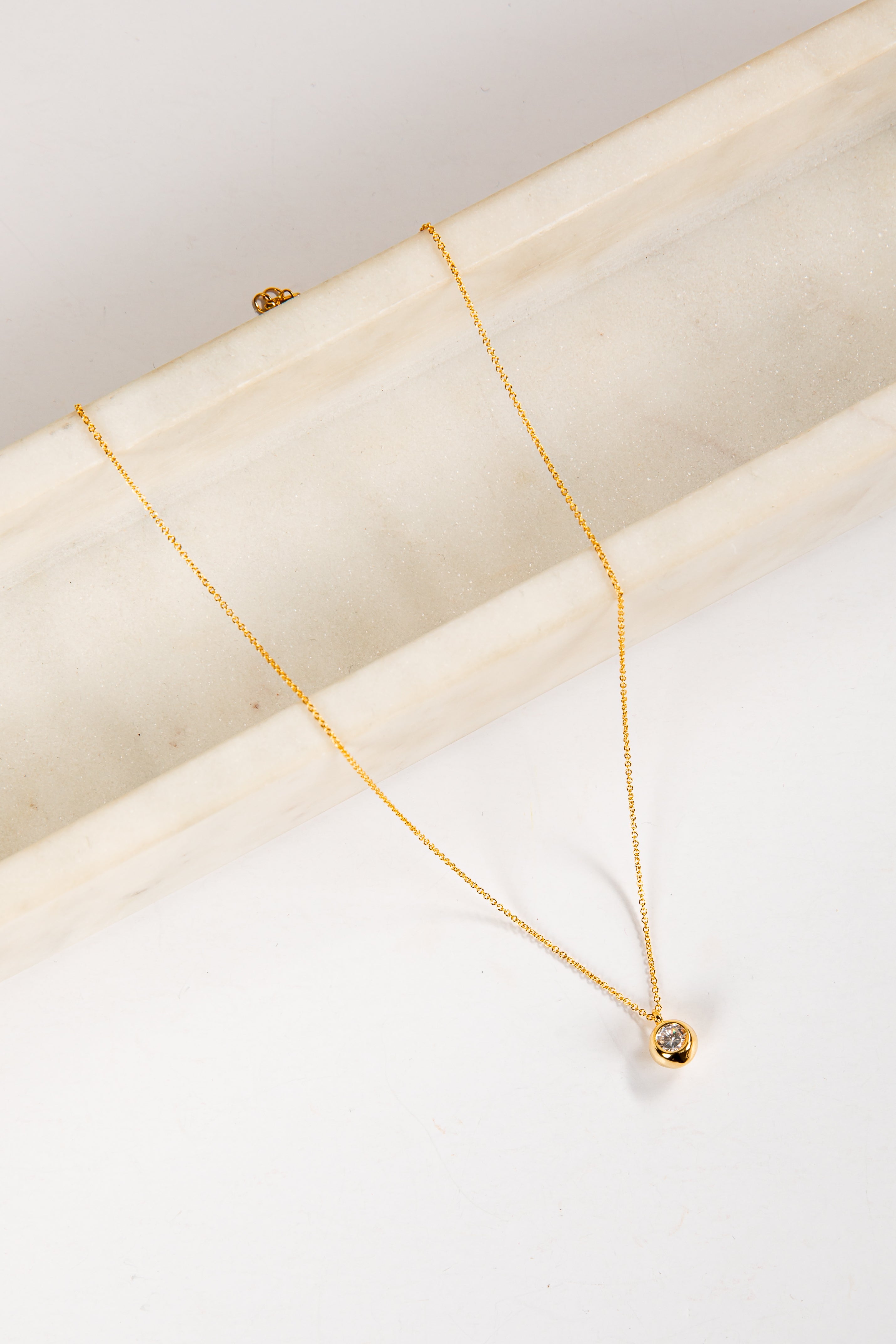 Gold necklace on a white marble surface