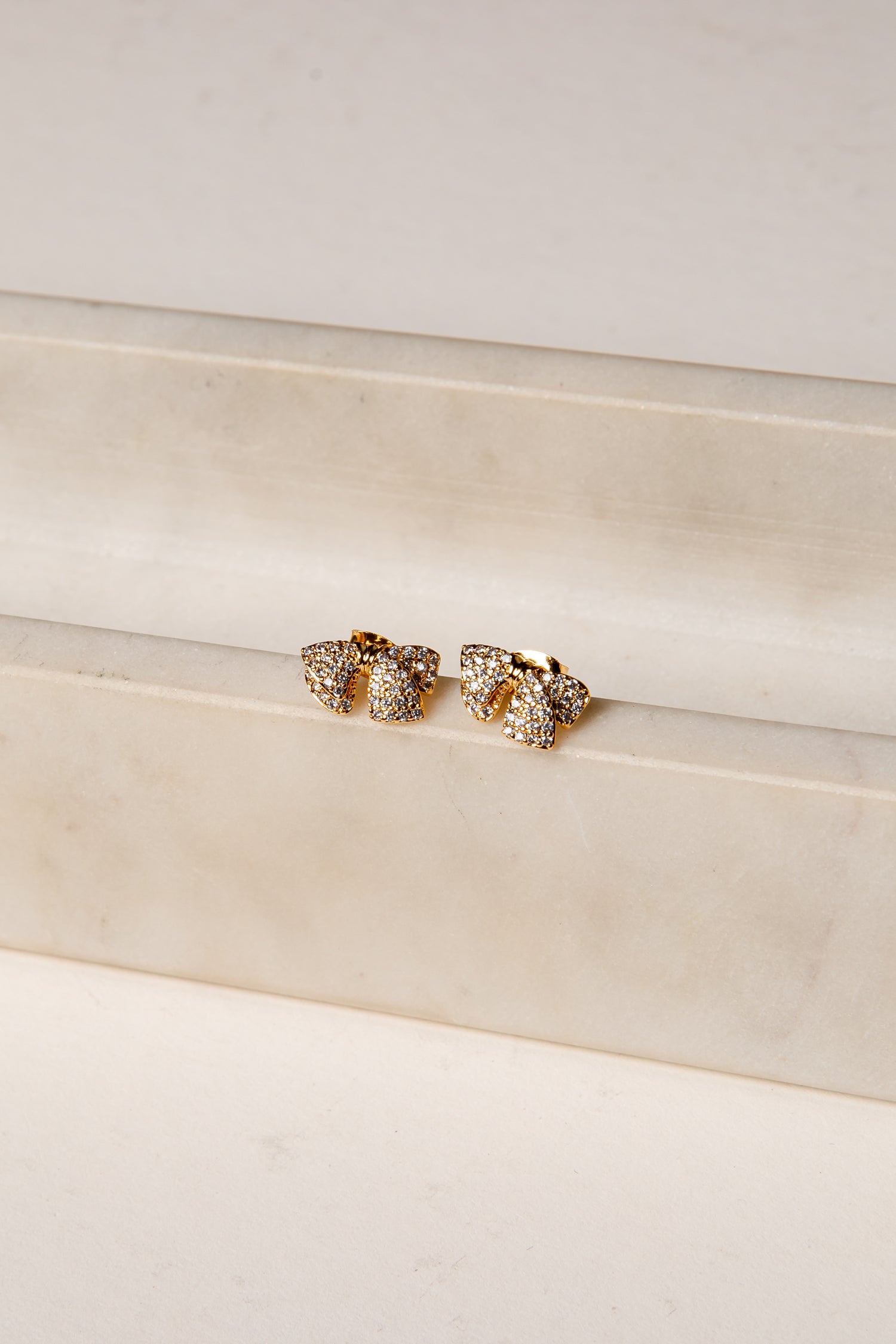 Gold earrings on a white surface