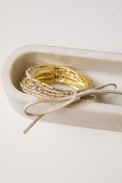 Gold bracelets on a white dish with a beige ribbon