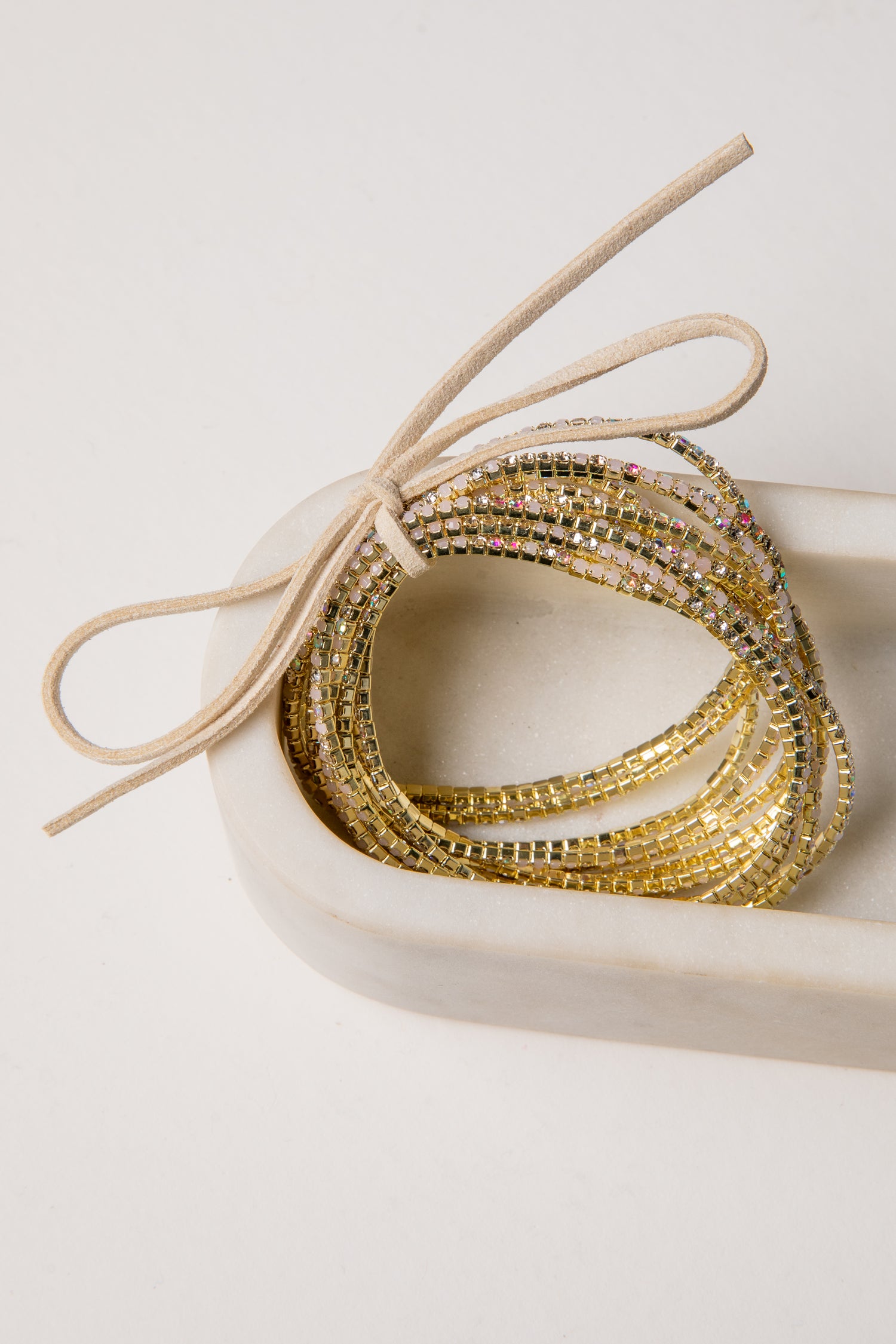 Gold beaded bracelets in a heart-shaped box on a light background