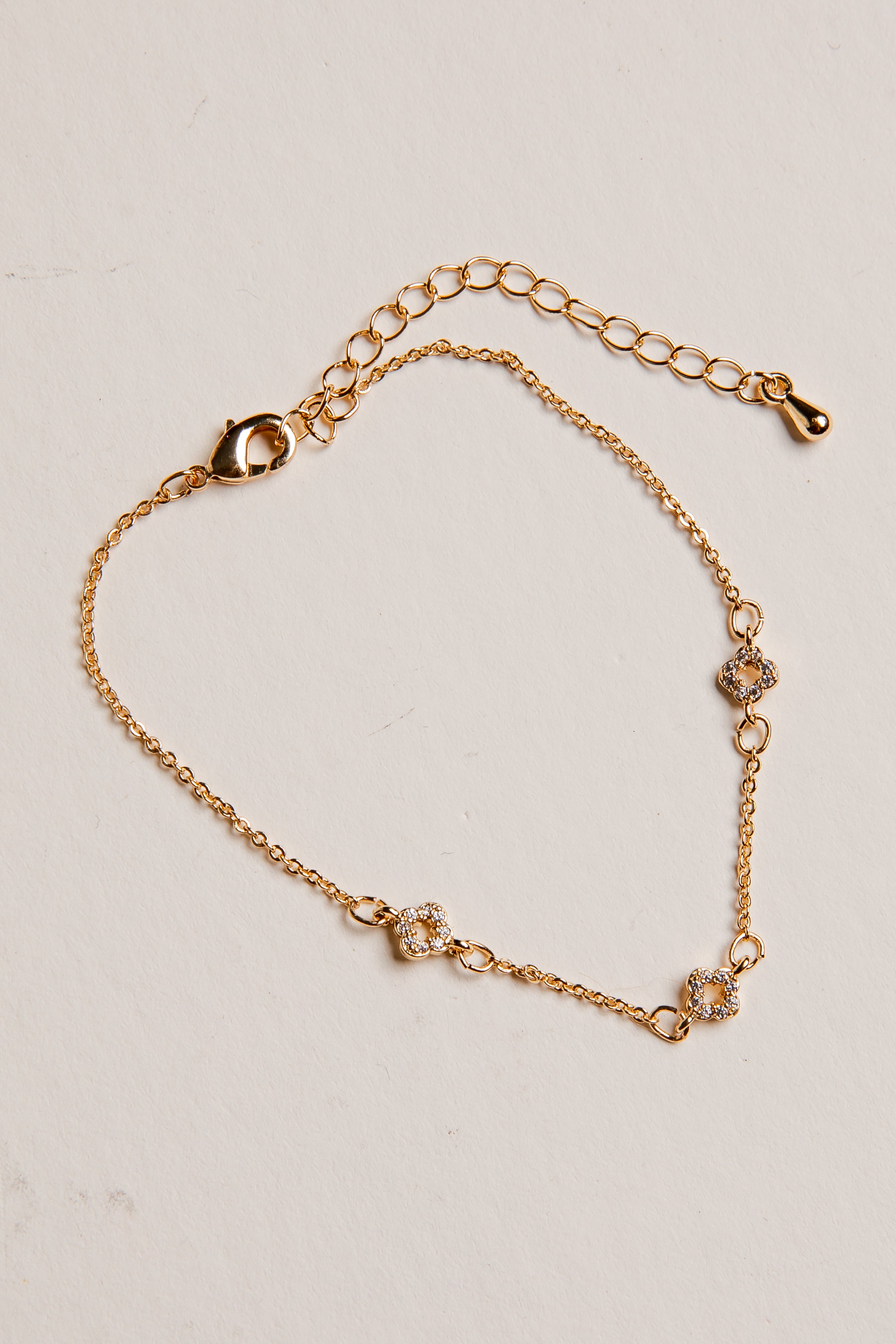 Gold bracelet with floral designs on a beige background