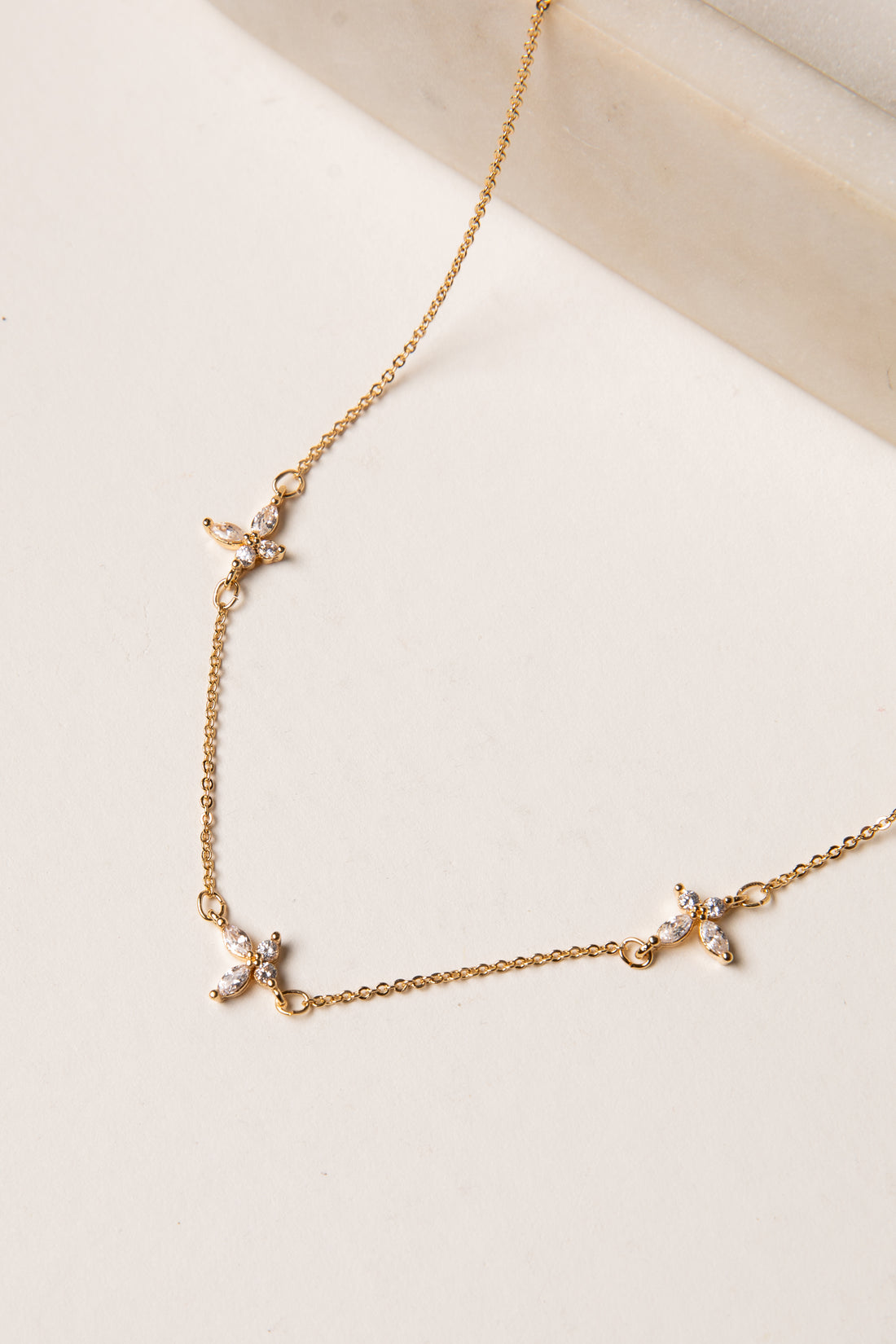 Gold necklace with small pendants on a beige background