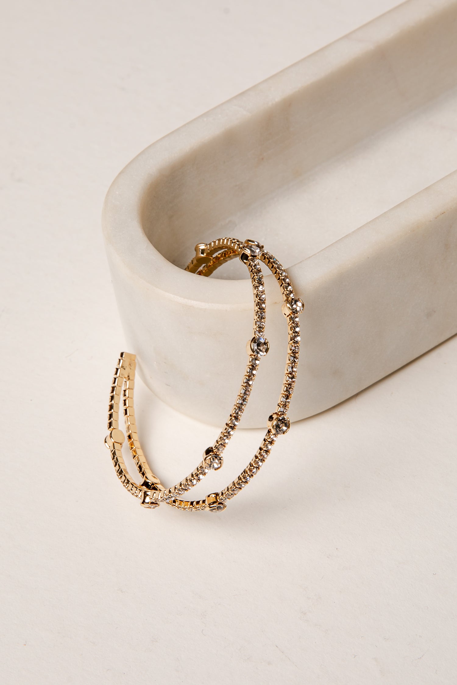 Gold bracelet on a white ceramic dish