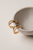 Gold hoop earrings on a light gray surface with a neutral background