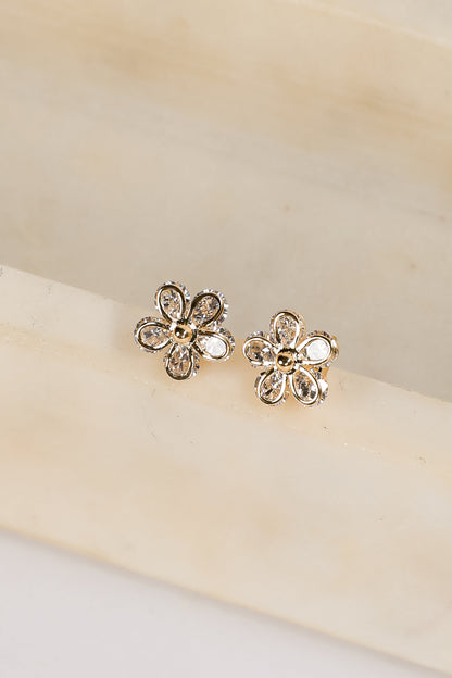 Gold flower-shaped earrings on a beige background