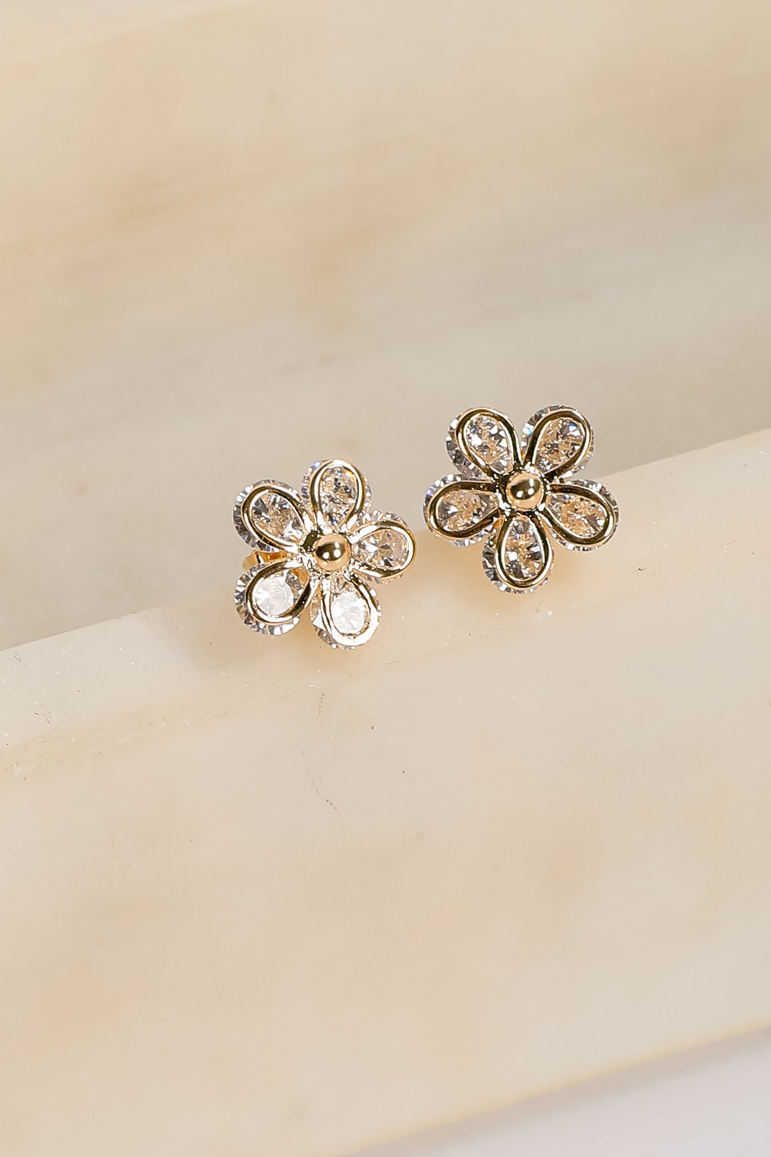 Flower-shaped earrings on a beige surface
