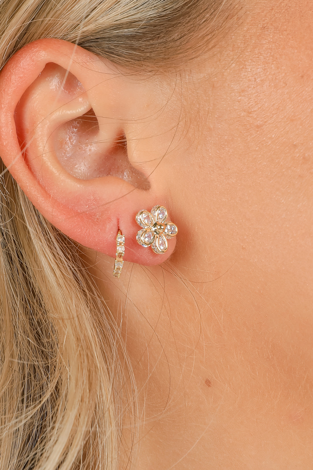 Close-up of an ear wearing a floral earring with pearl accents.
