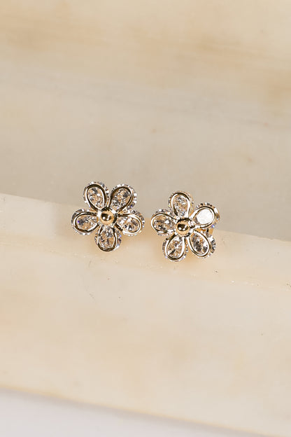 Flower-shaped earrings with clear stones on a beige background