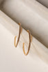 Gold hoop earrings with embedded stones on a marble surface