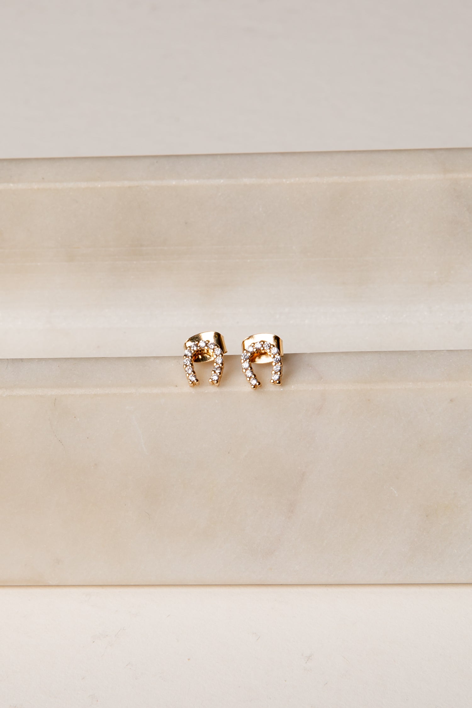 Rose gold elephant earrings on a beige background