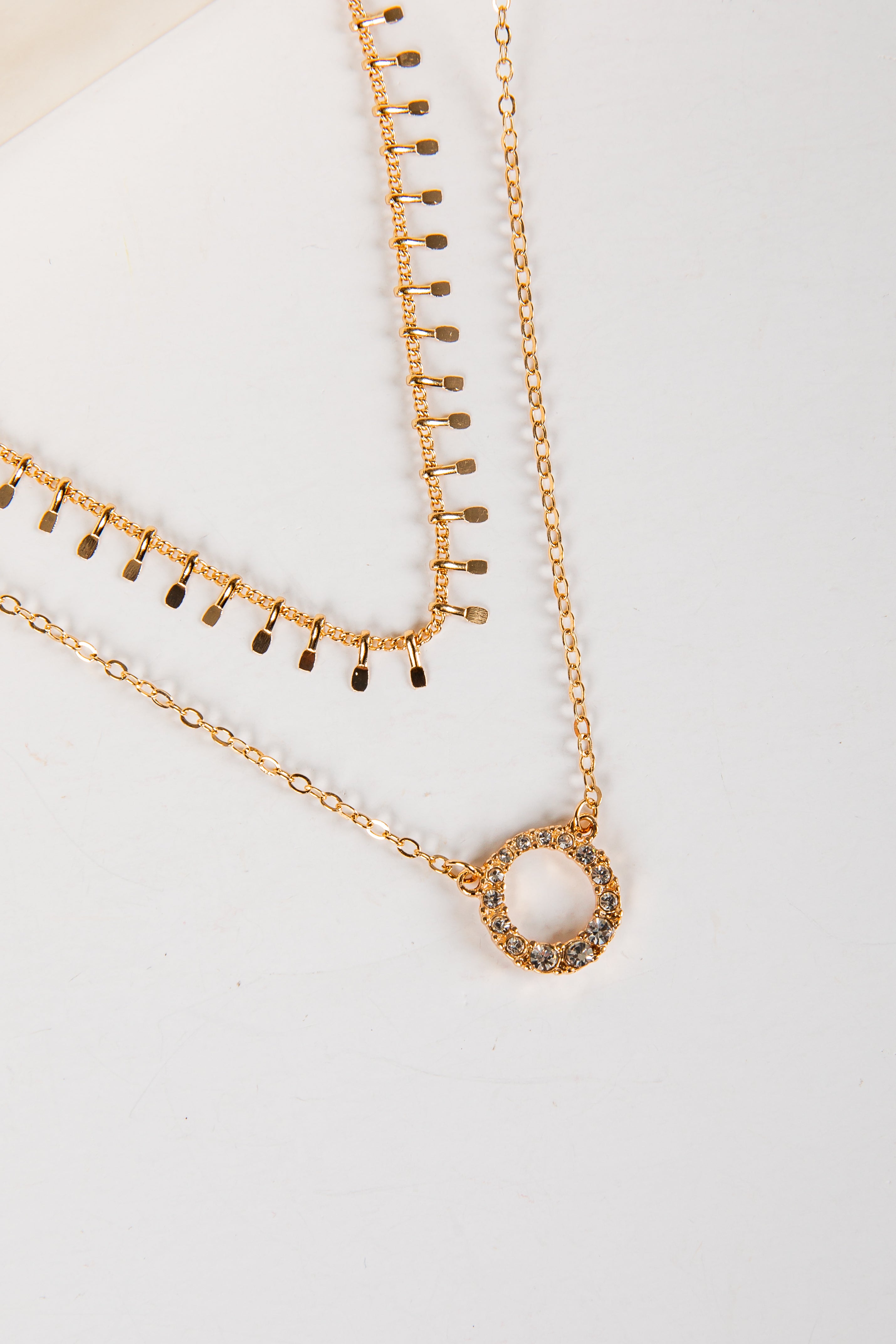 Two gold necklaces on a light gray background