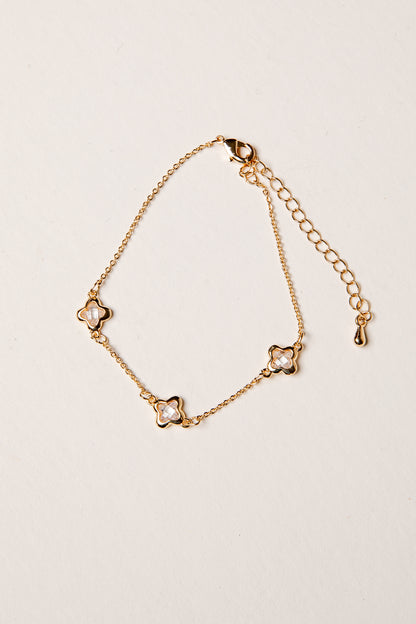 Gold bracelet with star-shaped clasps on a beige background