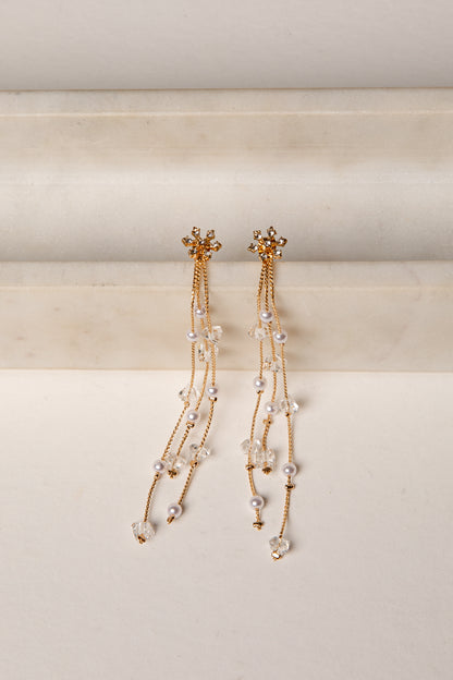 Pair of gold and pearl earrings on a beige background