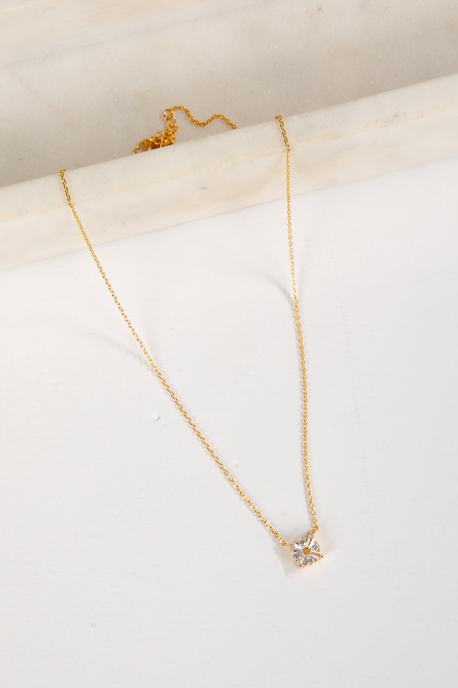 Gold necklace with a star-shaped pendant on a white surface