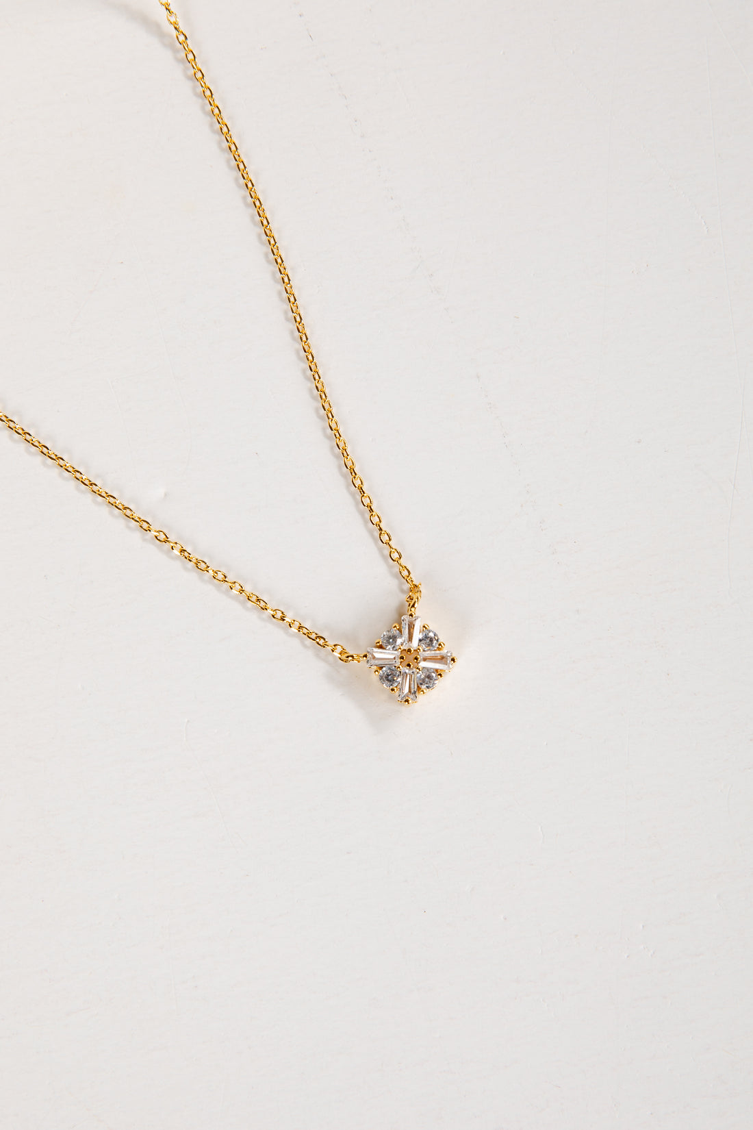 Gold necklace with a star-shaped pendant on a light gray background