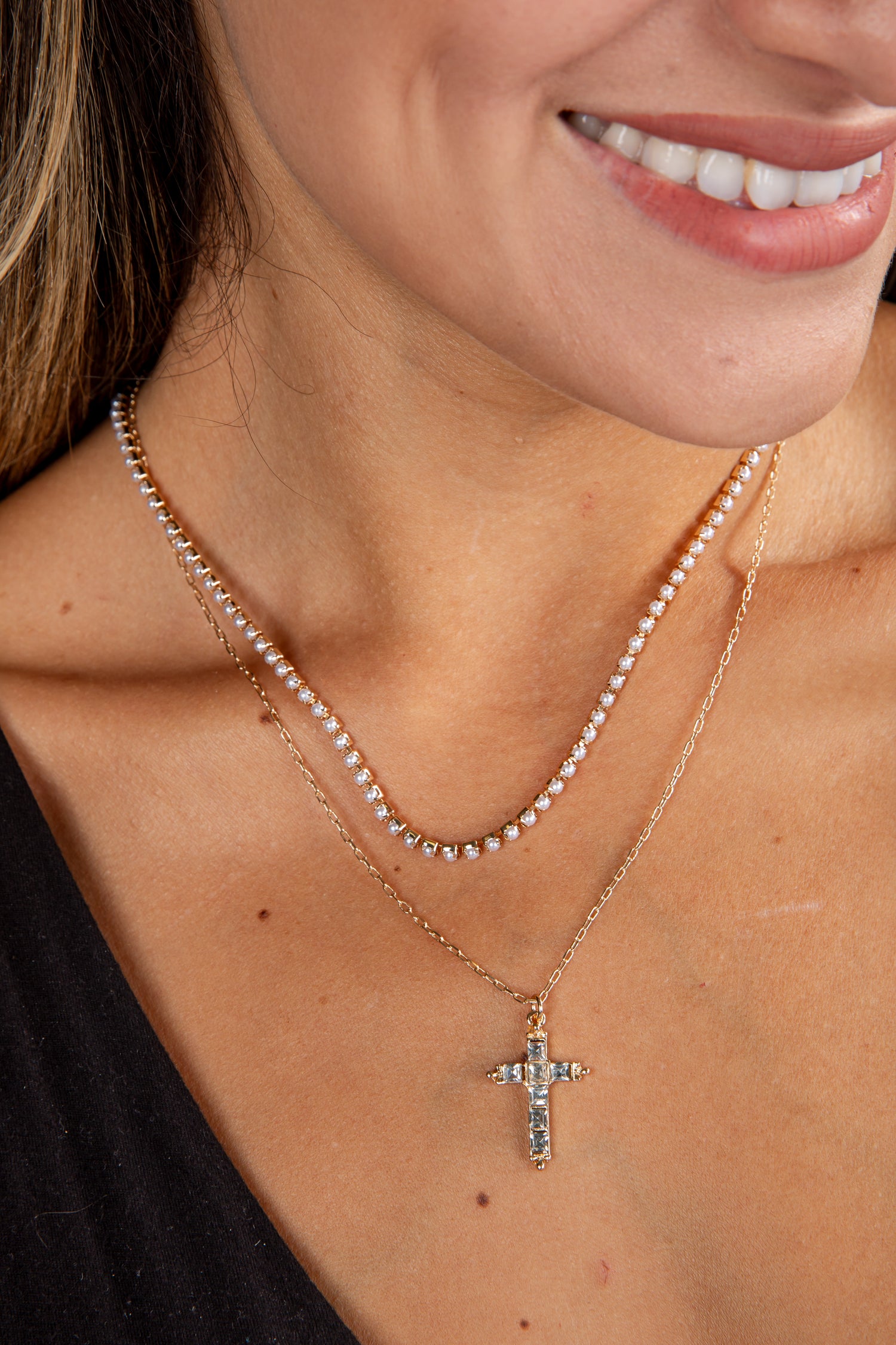 Close-up of a woman wearing a gold necklace with a cross pendant.
