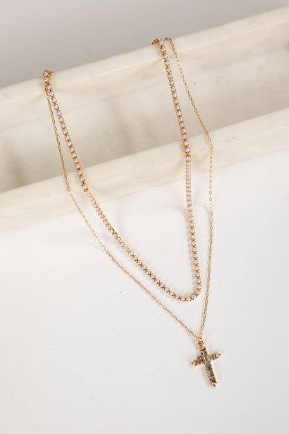 Two gold necklaces with a cross pendant on a white surface