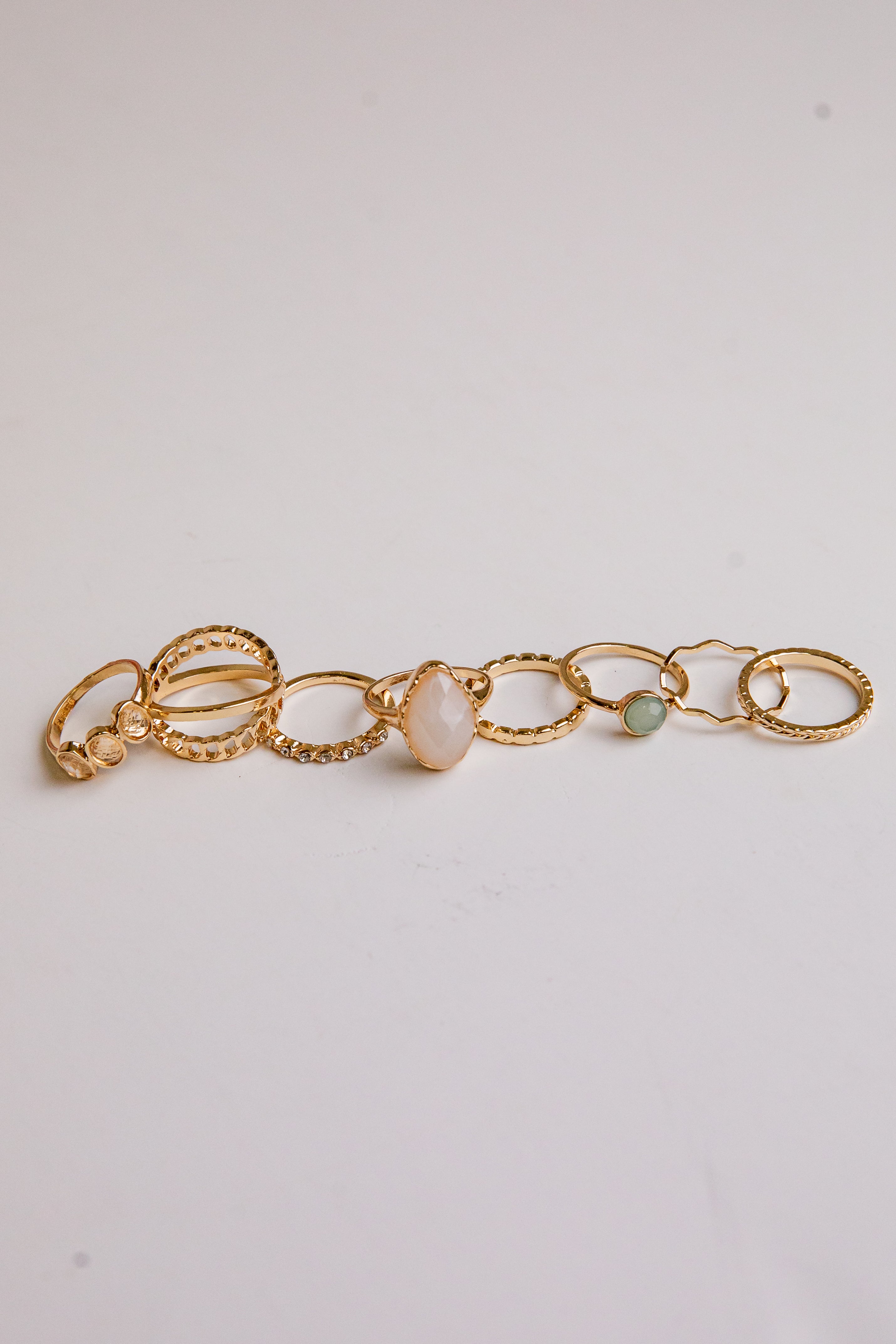 Gold bracelet with three beads on a light gray background