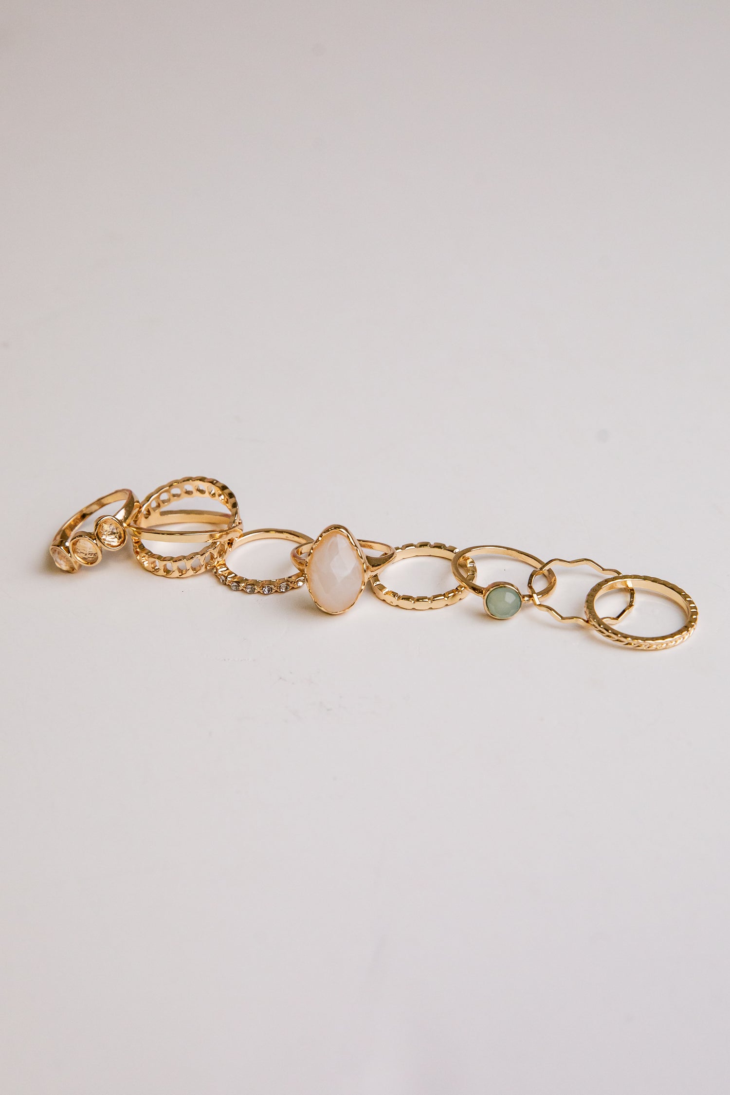 Gold bracelet with circular links and stones on a light gray background